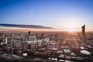 panoramic view of the built up Manchester skyline at dawn with the sun rising.