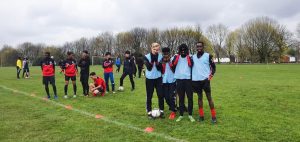 4 young footballers stood together smile at camera